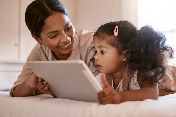 Vind je het mooi? Foto van een klein meisje met behulp van een digitale tablet met haar moeder thuis. — Stockfoto
