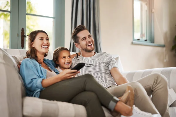 Beter dan in de bioscoop. Shot van een gelukkig jong gezin ontspannen op de bank en tv kijken samen thuis. — Stockfoto