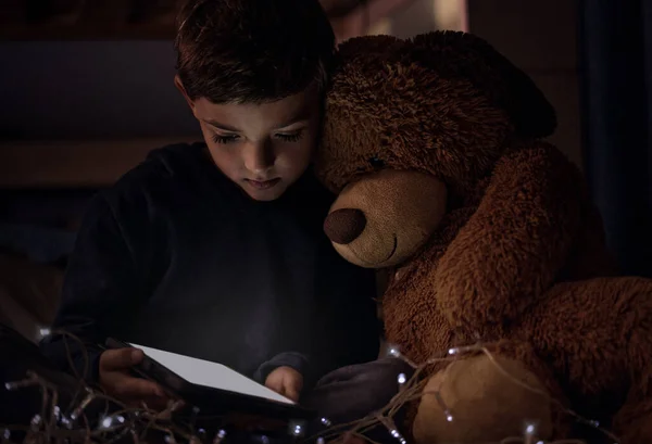 Il regno appartiene ai bambini piccoli. Girato di un adorabile ragazzino usando un tablet digitale con il suo orsacchiotto di notte nella sua camera da letto. — Foto Stock
