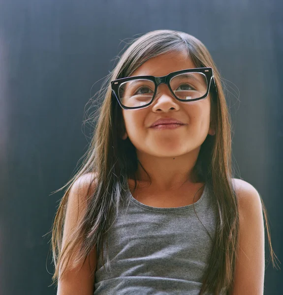 Si interroga sempre sul mondo. Studio foto di una bambina che indossa occhiali su uno sfondo scuro. — Foto Stock