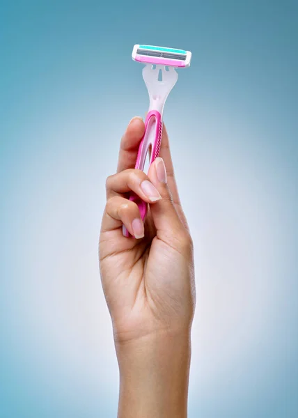 Its grooming day. Cropped shot of an unrecognisable woman holding a shaving stick against a blue background in the studio.