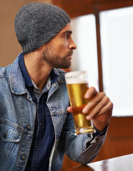 Lasst uns diesen Durst stillen. Aufnahme eines gut aussehenden jungen Mannes, der an der Bar ein Bier trinkt. — Stockfoto