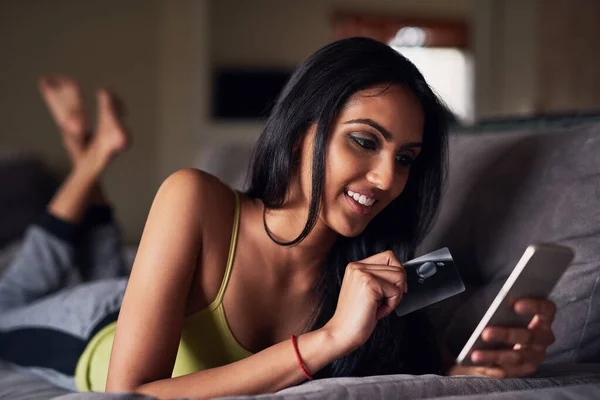 Apps erleichtern das Einkaufen enorm. Aufnahme einer attraktiven jungen Frau beim Online-Shopping, während sie zu Hause auf dem Sofa liegt. — Stockfoto