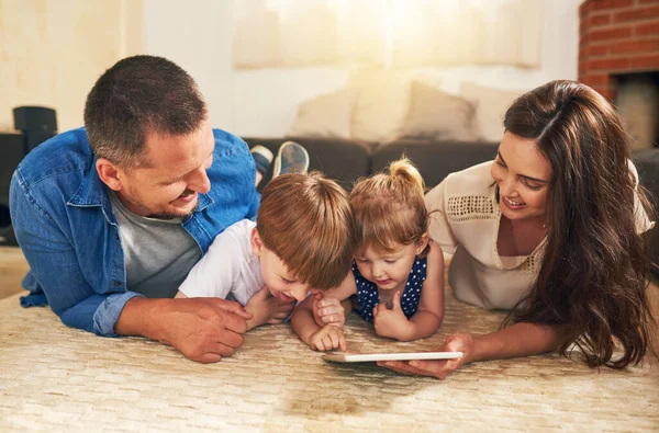 Η τεχνολογική οικογένεια είναι πιο συνδεδεμένη από ποτέ. Πυροβολισμός ενός αξιολάτρευτου αδελφού και αδελφής χρησιμοποιώντας ένα ψηφιακό tablet με τους γονείς τους στο πάτωμα στο σπίτι. — Φωτογραφία Αρχείου