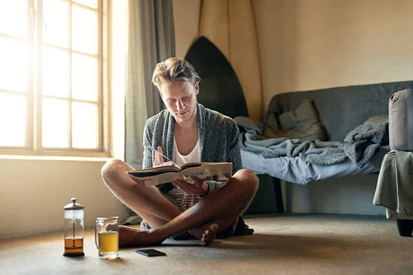 Není nad dobrou otočku stránky. Zastřelen mladým mužem, který čte knihu doma. — Stock fotografie