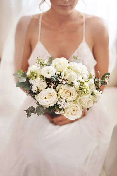Ένα γλυκό τέλος σε μια νέα αρχή. Τραβηγμένο πλάνο μιας ελκυστικής νεαρής νύφης που κάθεται μόνη στο καμαρίνι και κρατάει το μπουκέτο με τα λουλούδια της.. — Φωτογραφία Αρχείου