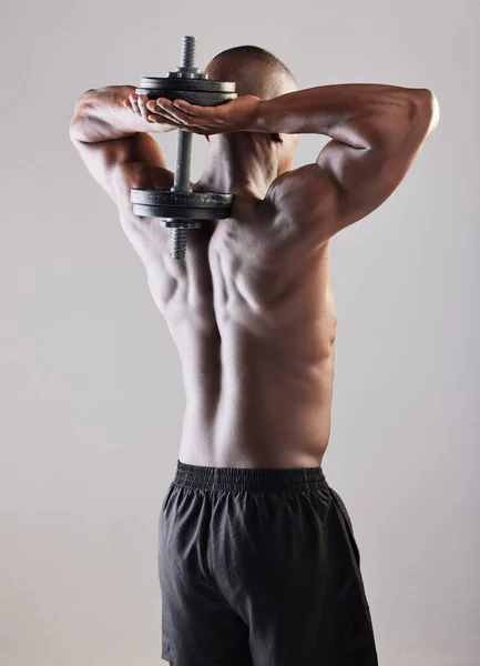 Plus c'est lourd, mieux c'est. Vue arrière d'un jeune homme musclé posant sur un fond gris. — Photo