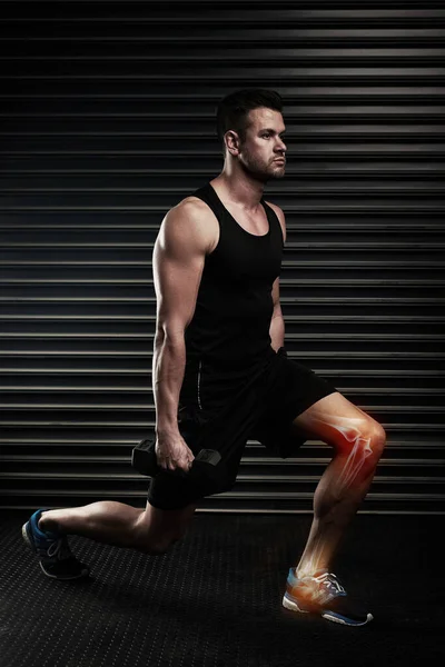 Los brotes pueden poner tensión en las rodillas. Largometraje de un joven atlético haciendo ejercicio con pesas en el estudio. —  Fotos de Stock