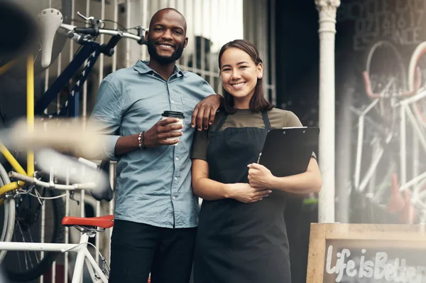 Permet de vous obtenir le vélo de vos rêves. Prise de vue de deux jeunes propriétaires d'entreprise debout devant leur magasin de vélos pendant la journée. — Photo