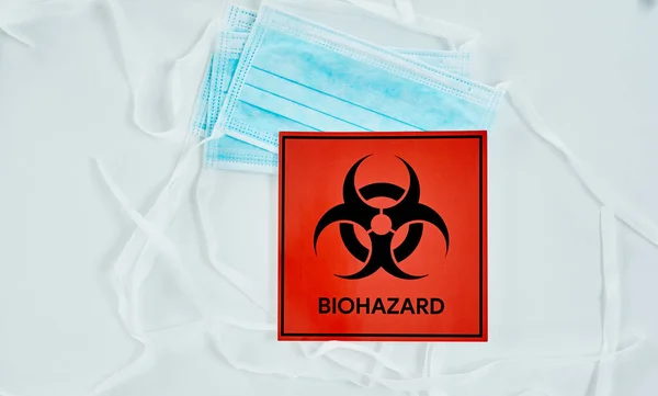 Stellen Sie sicher, dass Sie die Biohazard-Protokolle befolgen. Aufnahme eines Biohazard-Schildes und einer Gesichtsmaske vor weißem Hintergrund. — Stockfoto