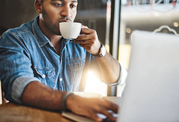 El café lo mantiene concentrado. Tiro de un joven guapo bebiendo café mientras trabajaba en un café. — Foto de Stock