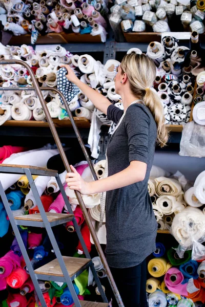 Ela tem olho para o material certo. Uma assistente de loja feminina selecionando um material adequado de uma prateleira. — Fotografia de Stock