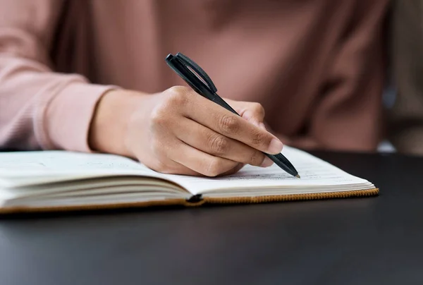 Nunca renuncies a tus metas. Fotografía de una mujer irreconocible escribiendo en un cuaderno mientras trabajaba desde casa. —  Fotos de Stock