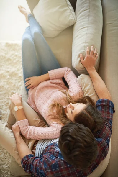 Des câlins sur le canapé. Tourné d'un jeune couple heureux se détendre sur le canapé à la maison. — Photo