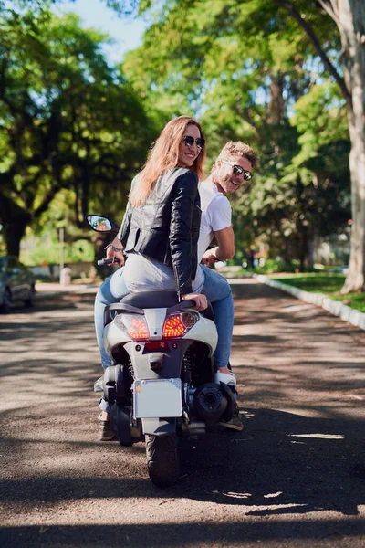Ve a explorar con el que adoras. Vista trasera de una joven pareja atractiva montando un scooter por la ciudad. — Foto de Stock