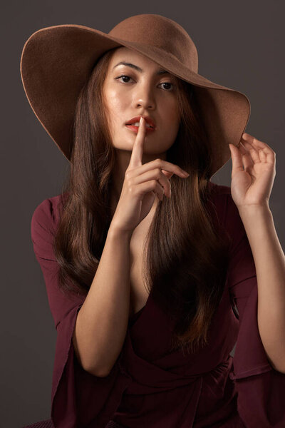 Dont say a word. Cropped portrait of an attractive young woman posing with her finger on her lips in studio against a grey background.