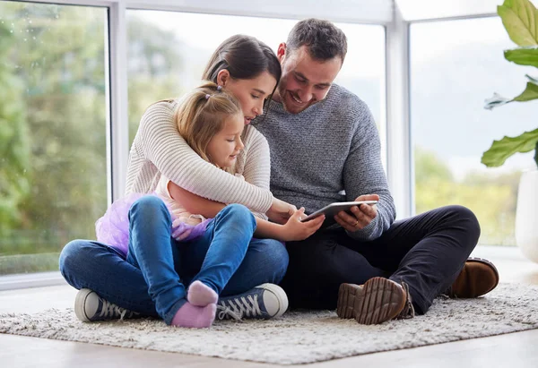 Happiness personified. Shot of a young family using a digital tablet at home. — Stock Photo, Image
