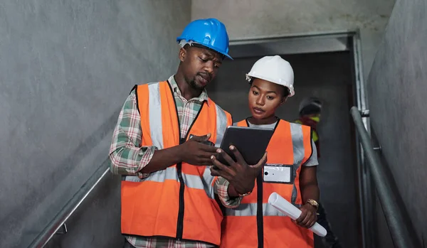 Az építőmunkások azt teszik, amire születtek. Egy fiatal férfi és nő digitális táblagépet használ, miközben egy építkezésen dolgozik.. — Stock Fotó