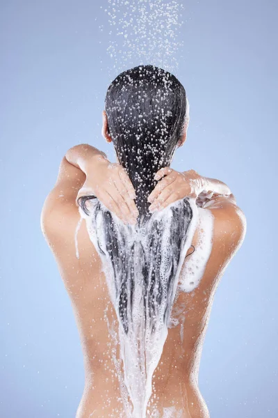 Lave o dia. Tiro de uma mulher irreconhecível lavando o cabelo no chuveiro contra um fundo azul. — Fotografia de Stock