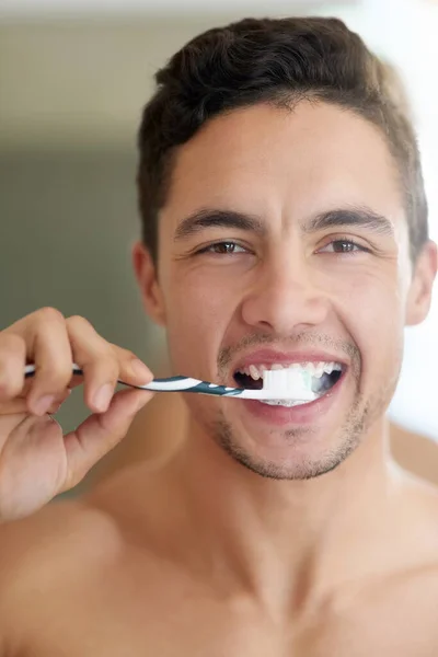 Os germes não têm hipótese. Tiro de um jovem bonito escovando os dentes em casa. — Fotografia de Stock