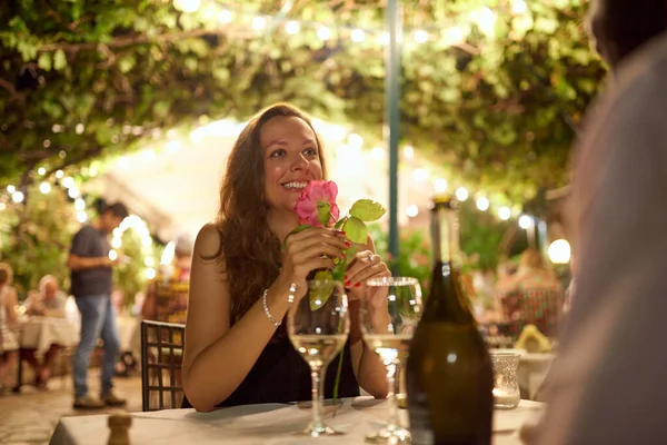 Ik ben nog nooit zo speciaal behandeld. Schot van een vrouw die een roos ontvangt van haar date in een restaurant.. — Stockfoto