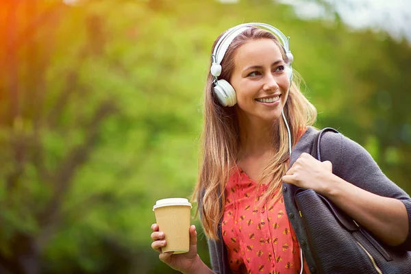 Prenez votre musique et votre café avec vous. Tourné d'une jeune femme écoutant de la musique tout en prenant un café sur le pouce. — Photo