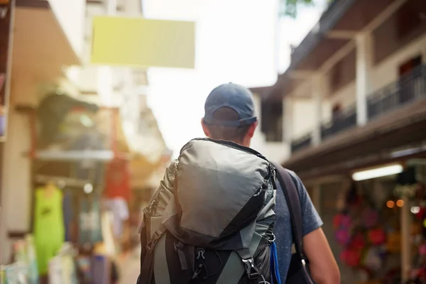 Há um mundo inteiro lá fora. Foto retrovisada de um jovem turista usando uma mochila andando pela rua da cidade. — Fotografia de Stock