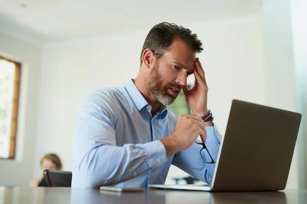 Quando o estresse no trabalho invade a vida doméstica. Tiro de um homem de negócios maduro olhando estressado ao usar um laptop para trabalhar em casa. — Fotografia de Stock