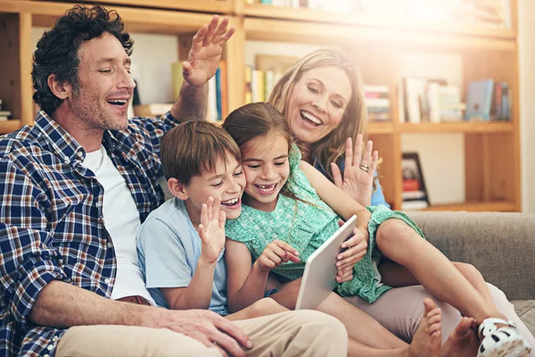 Grensoverschrijdend verbinden met slimme technologie. Opname van een gelukkig gezin dat samen thuis een videogesprek voert op hun digitale tablet. — Stockfoto