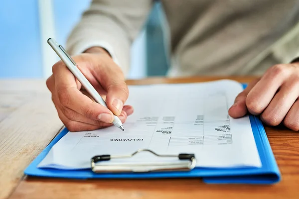 Er bekam die Antworten. Schnappschuss eines nicht wiederzuerkennenden Geschäftsmannes beim Ausfüllen von Papieren auf einem Klemmbrett, während er an einem Tisch in einem Büro sitzt. — Stockfoto