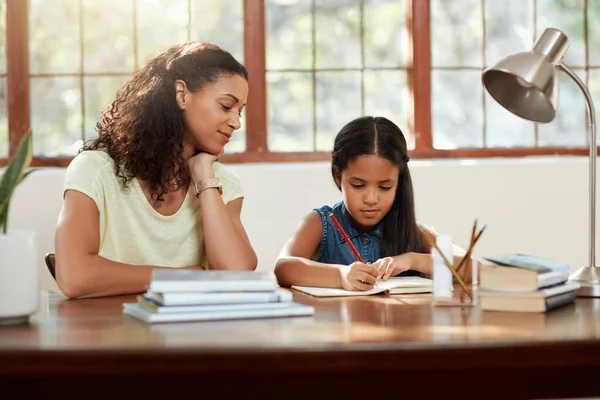 Ihr die Wichtigkeit von Bildung beibringen. Schnappschuss einer attraktiven jungen Mutter, die ihrer Tochter bei den Hausaufgaben hilft. — Stockfoto