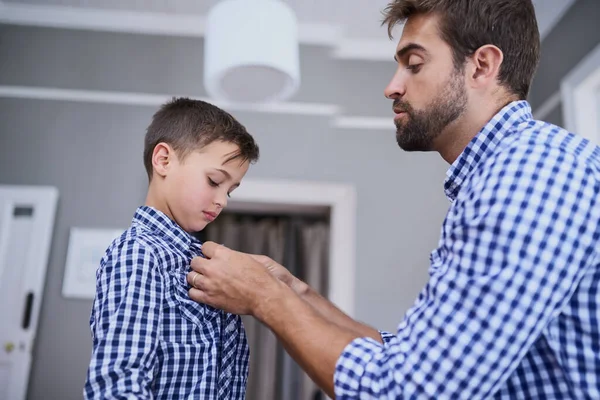 Pomůžu ti s tím knoflíkem. Vystřižený záběr pohledného mladého muže a jeho syna oblékání v dopoledních hodinách. — Stock fotografie