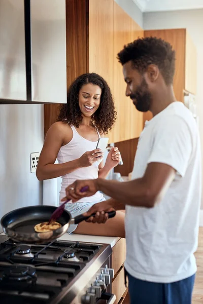 That looks good. Cropped shot of a handsome young man cooking in the kitchen while his wife watches on. — Stock Photo, Image