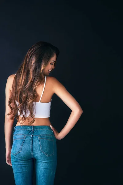 Showing off her silky, sleek curls. Studio shot of an attractive young woman posing against a dark background. — Stock Photo, Image