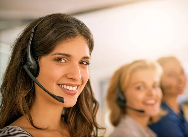 Servicio con una sonrisa. Retrato recortado de una joven que trabaja junto a sus colegas en un centro de llamadas. — Foto de Stock