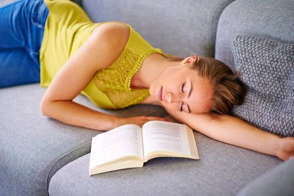Ничто так не расслабляет, как дом... Застрелен молодой женщиной, спящей рядом с книгой на диване дома. — стоковое фото