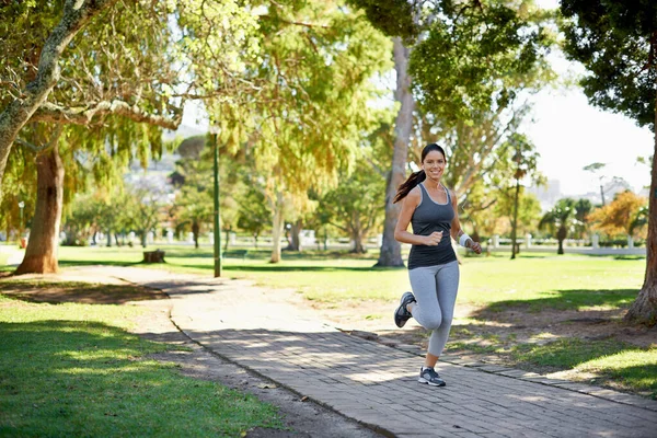 Adoro correr no parque. Tiro de comprimento total de uma jovem atraente correndo no parque. — Fotografia de Stock