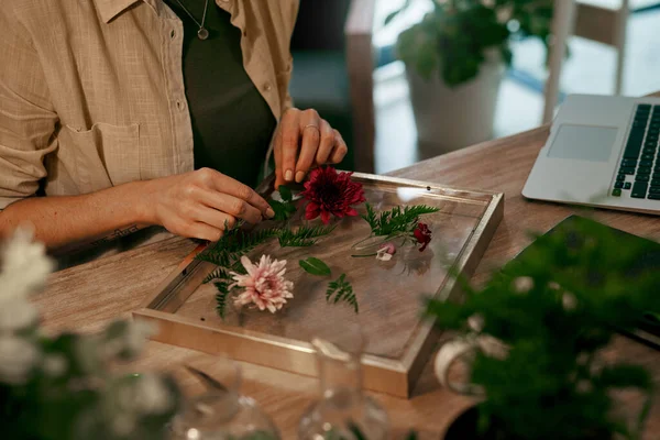 Está tudo a encaixar-se perfeitamente. Tiro cortado de uma florista irreconhecível decorando e pressionando flores em uma moldura de parede dentro de sua loja. — Fotografia de Stock