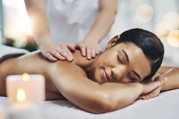 Het hoogtepunt van mijn dag. Shot van een ontspannen een vrolijke jonge vrouw het krijgen van een massage binnen in een spa. — Stockfoto