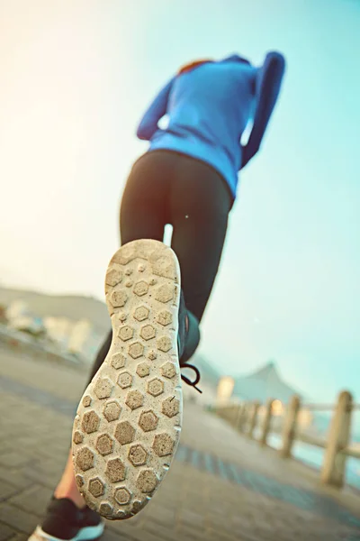 Beim Laufen ist das richtige Schuhwerk wichtig. Schuss einer sportlichen jungen Frau auf der Promenade. — Stockfoto