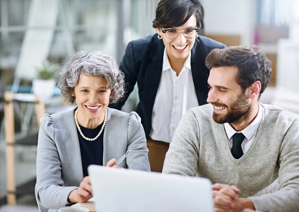 Ze zijn onder de indruk van hun vooruitgang tot nu toe. Opname van een groep zakenmensen die samenwerken op een laptop in een kantoor.. — Stockfoto