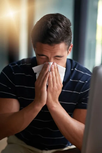 Sono arrivati i germi influenzali. Girato di un giovane uomo d'affari che si soffia il naso in un ufficio. — Foto Stock