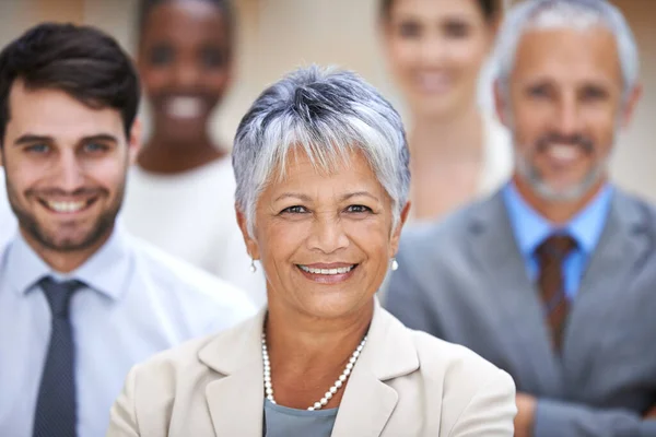 Positieve dingen gebeuren met positieve mensen. Portret van een lachende zakenvrouw omringd door een groep van haar collega 's. — Stockfoto