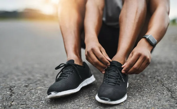 Du har inte råd att snubbla. Närbild skott av en sportig man binda sina skosnören när du tränar utomhus. — Stockfoto