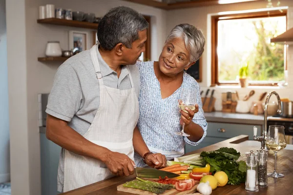 Het maken van hun pensioen een heerlijke. Shot van een gelukkig volwassen stel het drinken van wijn tijdens het koken van een maaltijd samen thuis. — Stockfoto