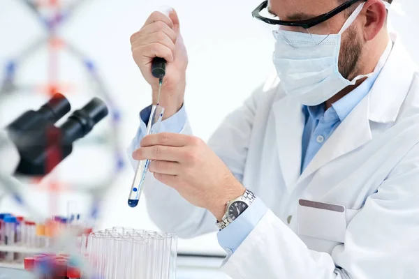 Opakuje experimenty, dokud nenajde výsledky, které potřebuje. Vystřižený snímek mužského vědce provádějícího experiment v laboratoři. — Stock fotografie