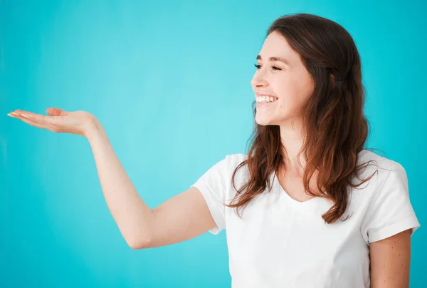 I swear by it. Studio shot of an attractive young woman posing with her hand out against a blue background. — Stock Photo, Image