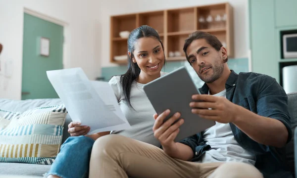 Lavorare per il nostro futuro un passo alla volta. Girato di una giovane coppia che fa scartoffie mentre usa un tablet digitale a casa. — Foto Stock