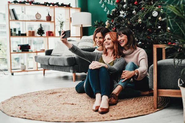 Birlikte selfie çekme zamanı. Noel zamanı üç çekici orta yaşlı kadının evde cep telefonuyla kendi portresini çekmesi.. — Stok fotoğraf