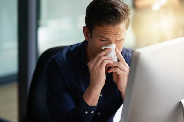 This cold is starting to torture me. Shot of a young businessman blowing his nose in an office. — Stock Photo, Image